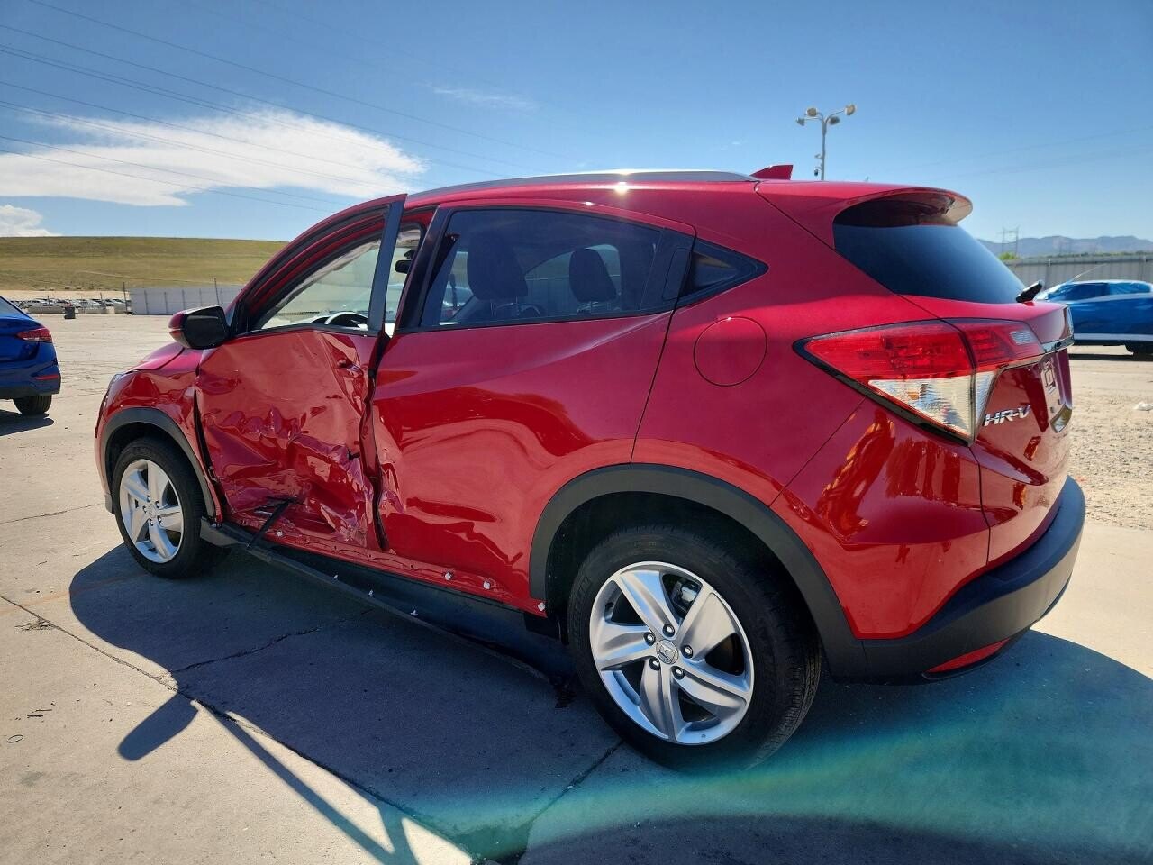 Red Honda HR V photographed in salvage condition at an auction yard